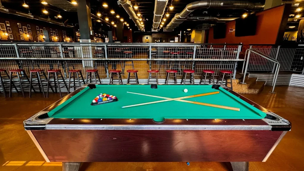 Green pool table ready for play in a modern industrial bar.
