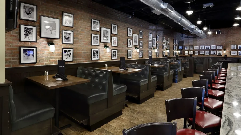 Empty rustic bar interior with booths, brick wall, and sports photos.