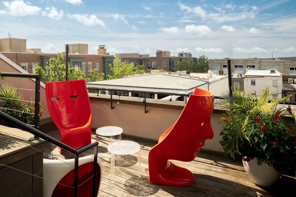 Two modern red face-design chairs on a sunny rooftop patio.