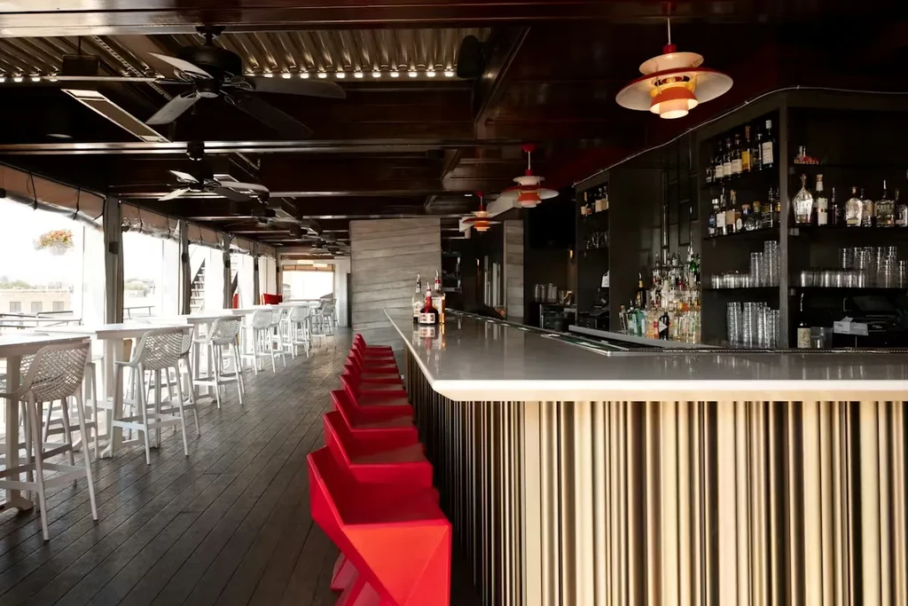 Empty modern bar with gold-ribbed counter and bright red stools.