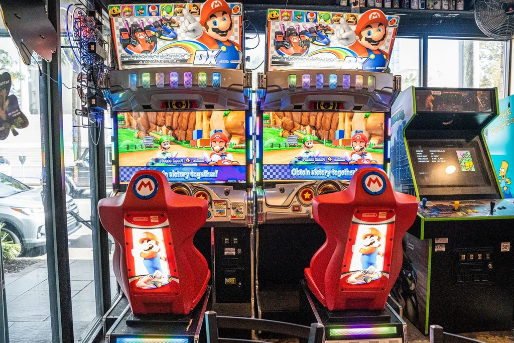 Two side-by-side Mario Kart DX arcade machines show gameplay.