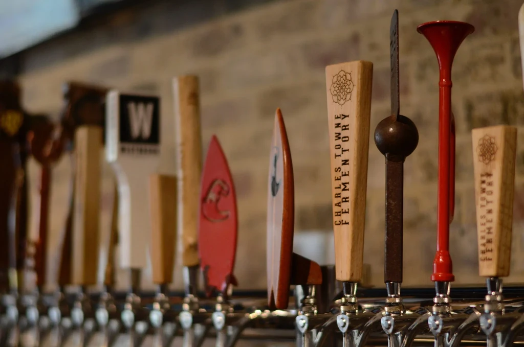 Close-up of diverse beer tap handles at a bar.