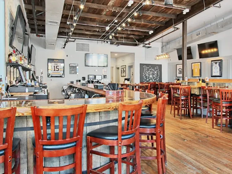 Empty rustic industrial sports bar interior with wooden bar and sports jerseys.