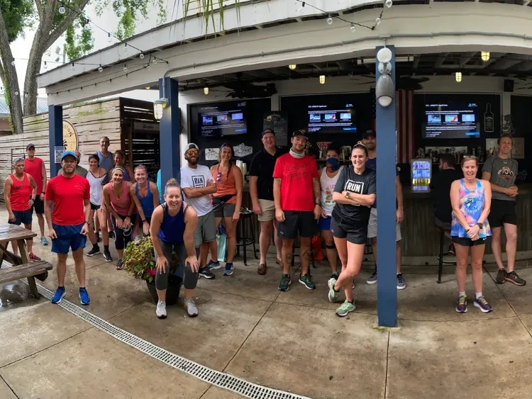 Smiling post-run group gathered at an outdoor bar patio.