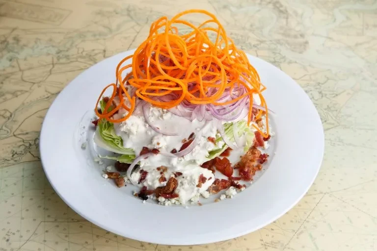Iceberg wedge salad with blue cheese, bacon, carrots, and red onion.