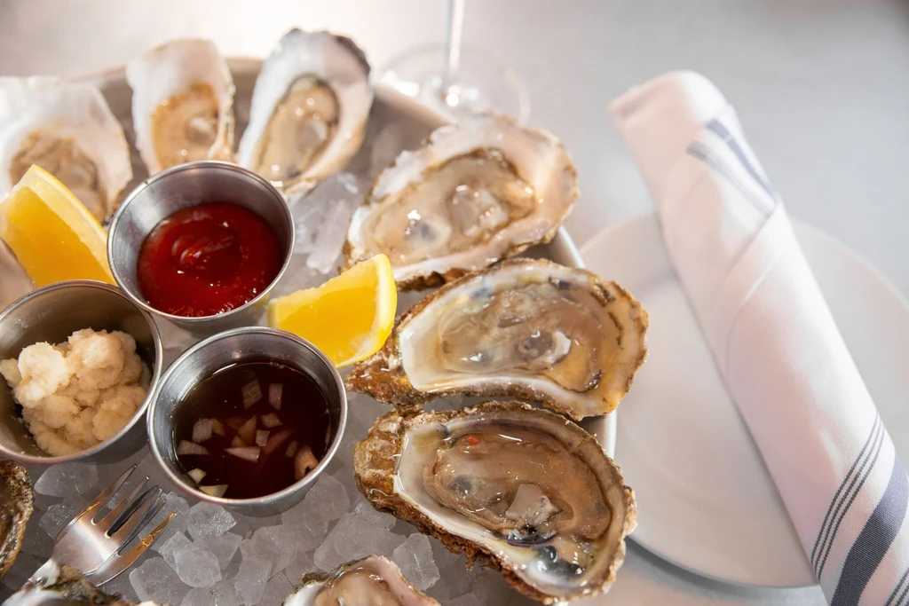 Freshly shucked oysters on ice with lemon, cocktail sauce, and mignonette.