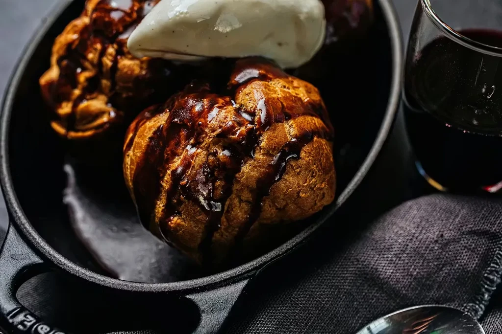 Golden choux pastries, chocolate sauce, light ice cream, and red wine.