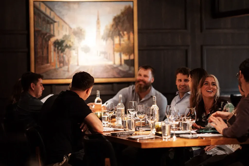 Seven diners laughing and conversing at a restaurant table.