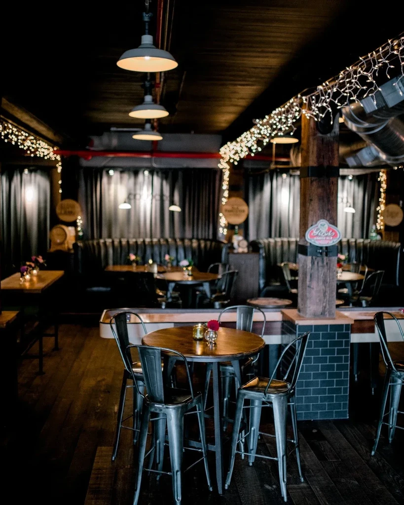 Dimly lit restaurant interior with industrial design and warm string lights.