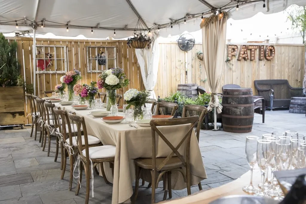 Elegantly set outdoor patio dining area with flowers, lights, 'PATIO' sign.