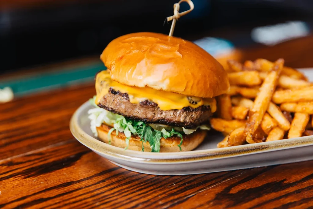Cheeseburger with melted cheese, lettuce, pickles, and golden fries.