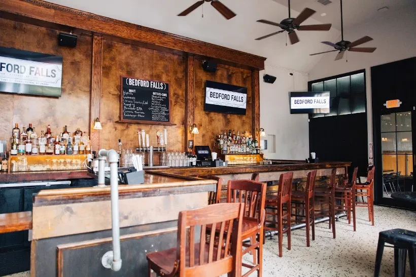 A wooden bar with liquor bottles, beer taps, and Bedford Falls branding.