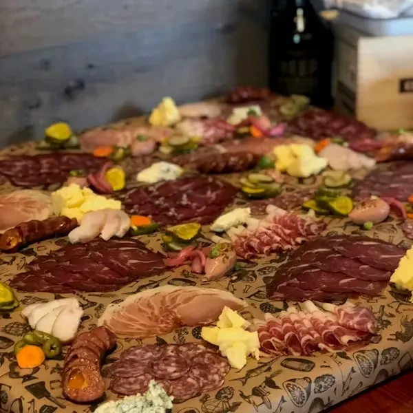 Abundant charcuterie spread with meats, cheeses, pickles, and seafood on paper.