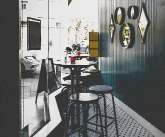 Modern cafe interior with high table, geometric floor, and window reflection.