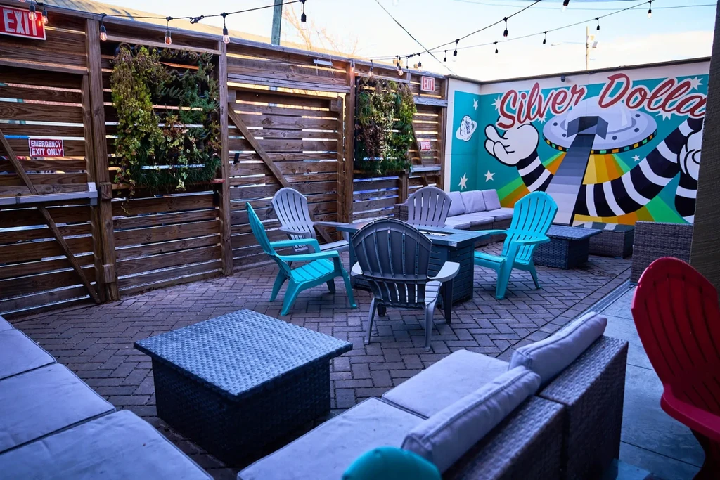 Outdoor patio with colorful UFO mural, vertical gardens, fire pit, seating.