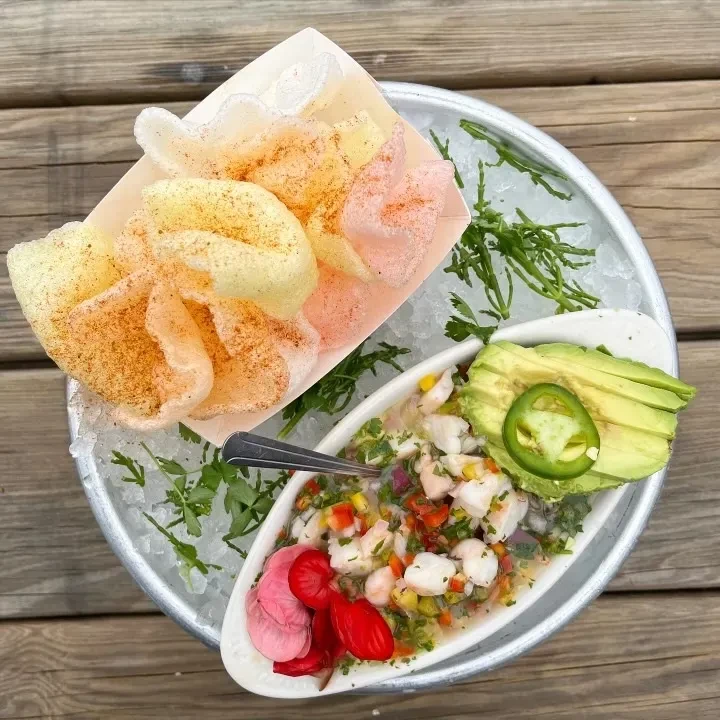 Overhead view of colorful ceviche with avocado, crackers, on crushed ice.