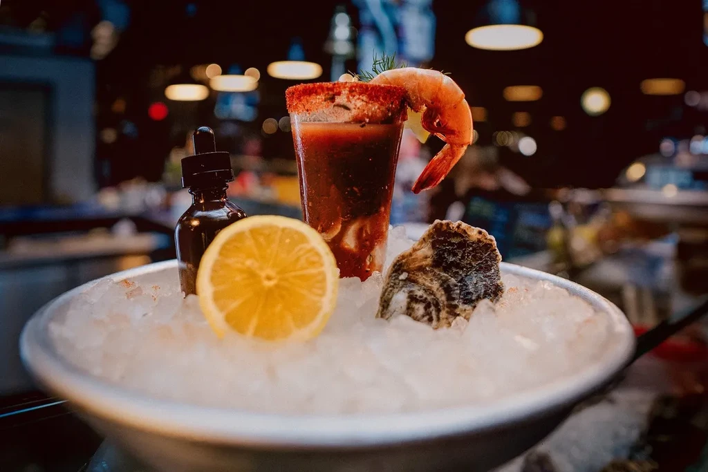 Bloody Mary, shrimp, oyster, lemon, and dropper bottle on crushed ice.