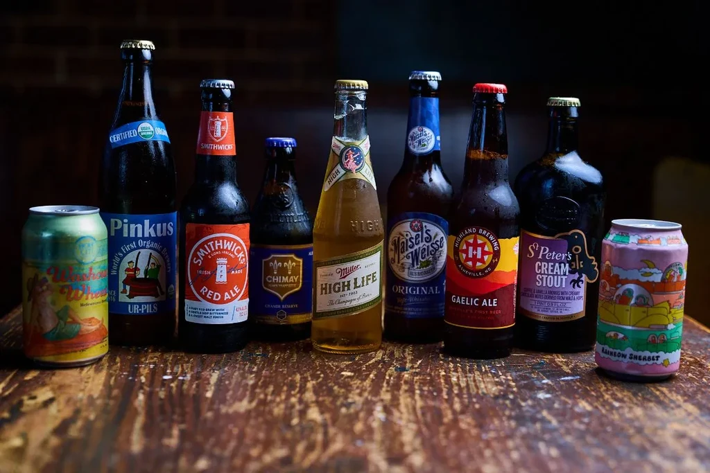 Ten chilled beer bottles and cans on a rustic wooden surface.