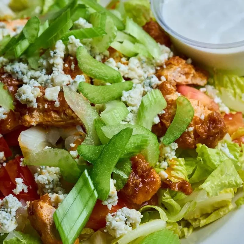 Close-up overhead Buffalo chicken salad with crispy chicken, blue cheese, dressing.