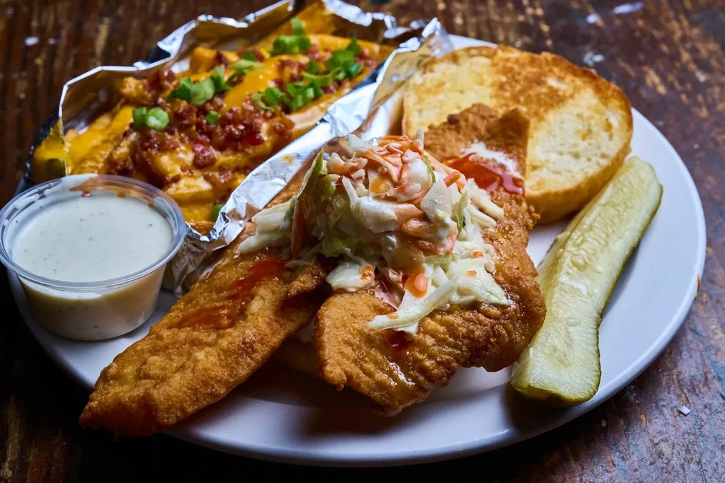 Fried fish sandwich, cheesy bacon fries, coleslaw, dipping sauce, and pickle.