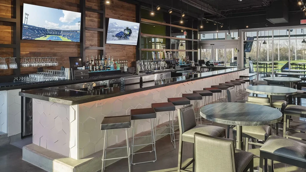 Modern, empty bar and restaurant with large TVs and outdoor view.