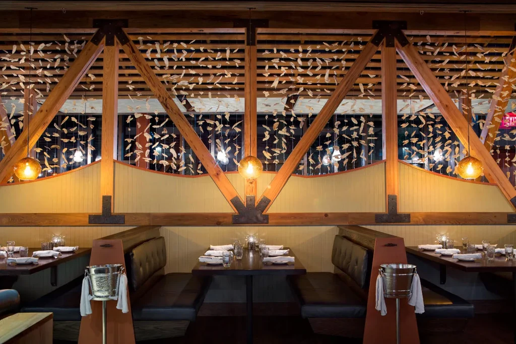 Restaurant interior: booths, wooden beams, suspended leaf screens, warm lighting.