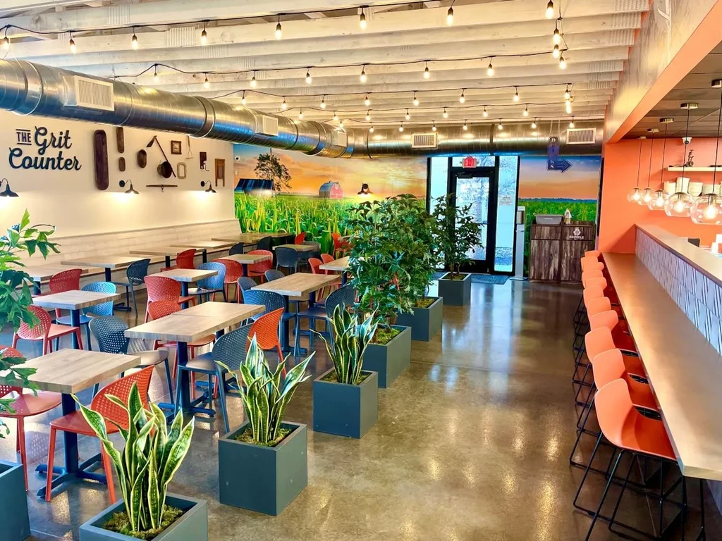 Contemporary restaurant "The Grit Counter" with bar, dining tables, and rural mural.