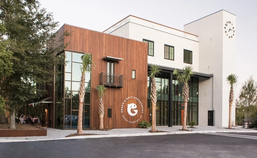 Modern Grace & Grit Restaurant exterior with wood, clock tower, palm trees.