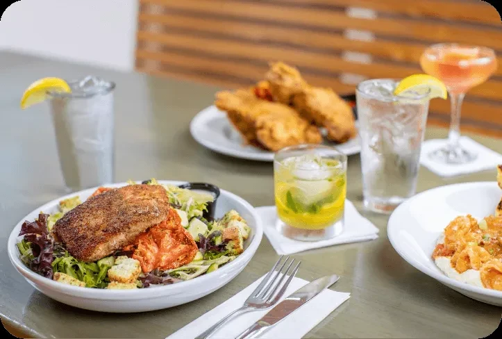 Restaurant table with salmon, shrimp, fried chicken, and cocktails.