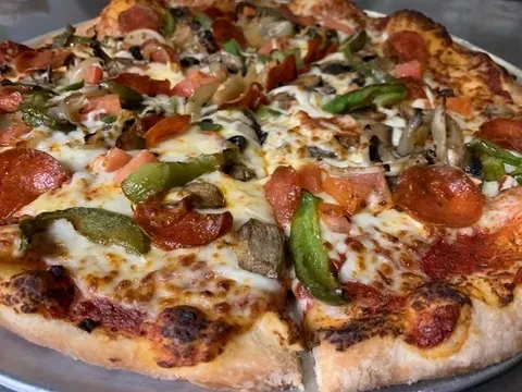 Freshly baked pizza with pepperoni, vegetables, and melted cheese.