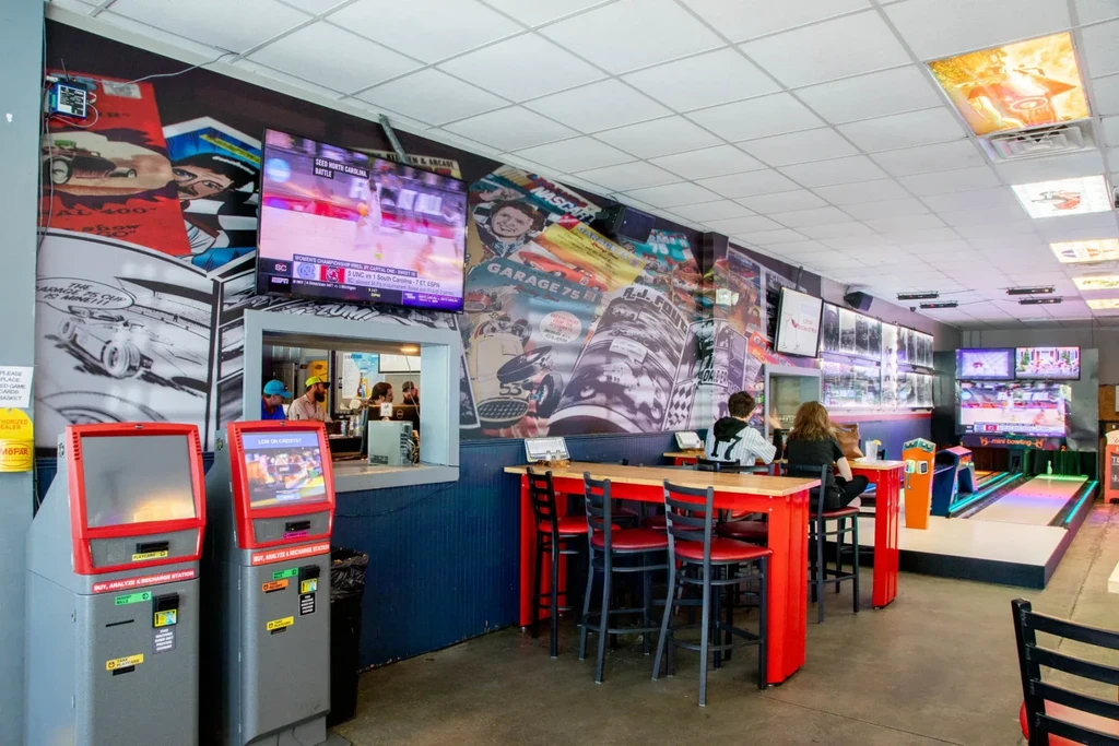 Sports bar interior with vintage racing murals, TVs, and bowling.