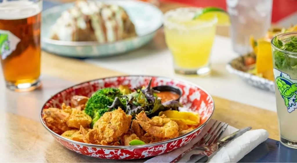 Crispy fried shrimp, broccoli, and greens on a speckled plate.
