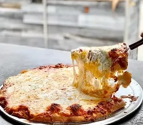 Hand lifts a slice of cheese pizza, creating a long cheese pull.