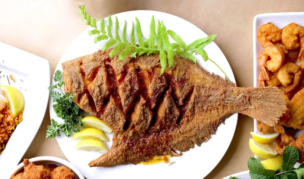 Top-down view of a fried fish, shrimp, rice, and other seafood.