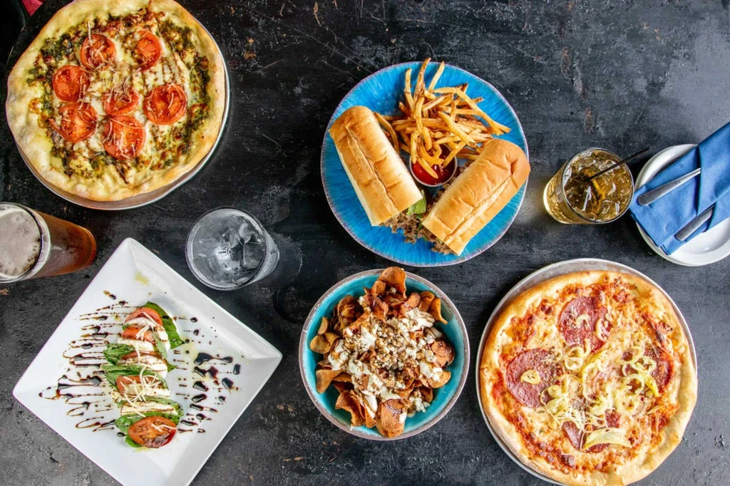 Overhead shot of multiple dishes and beverages on a dark table.