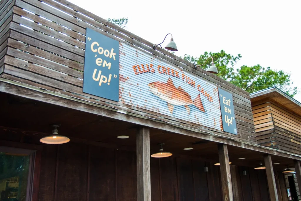 Weathered Ellis Creek Fish Camp exterior with prominent signs and fish.