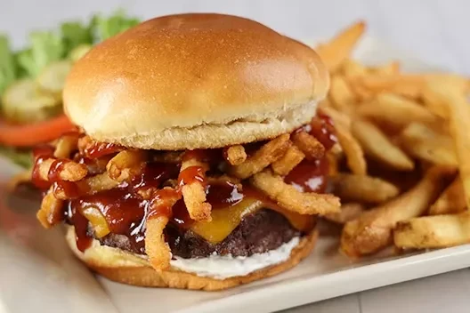 Hamburger with melted cheddar, barbecue sauce, crispy onions, and fries.