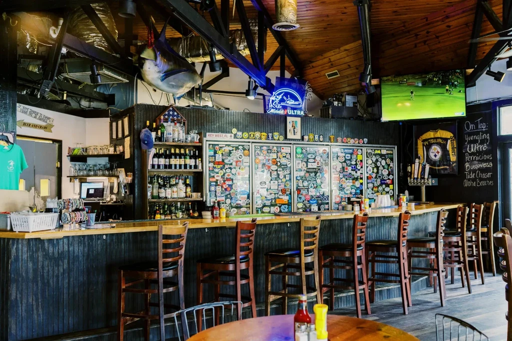 Rustic bar with long counter, beer taps, fish taxidermy, and sports TV.