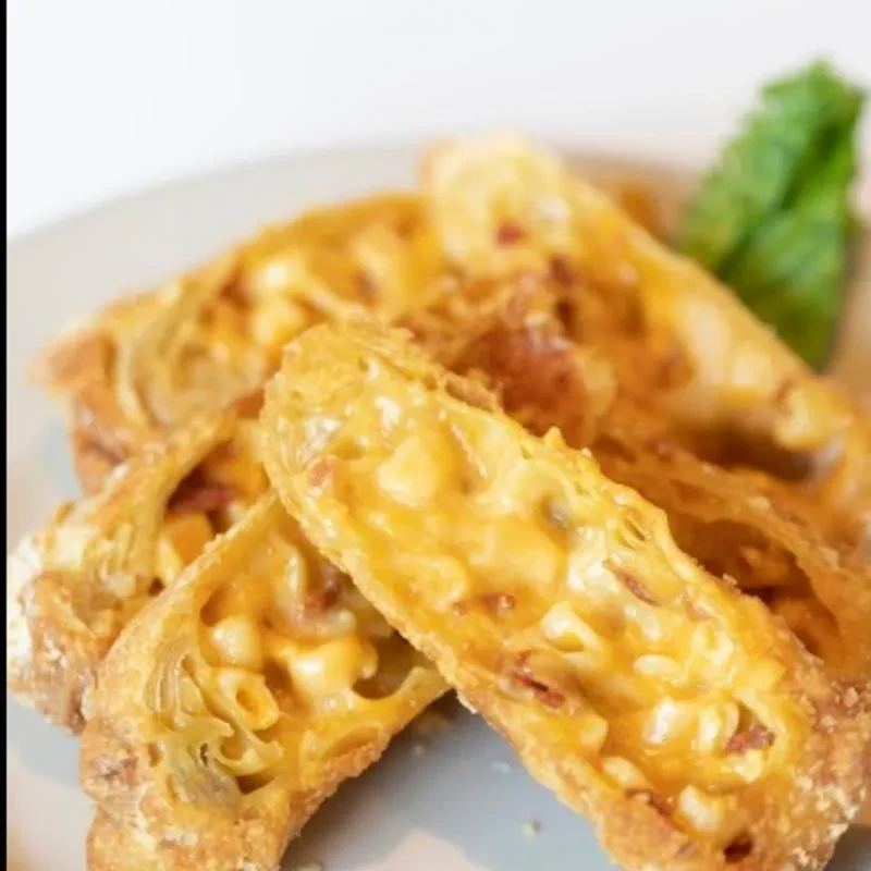 Golden fried rolls cut open, revealing creamy macaroni and cheese.