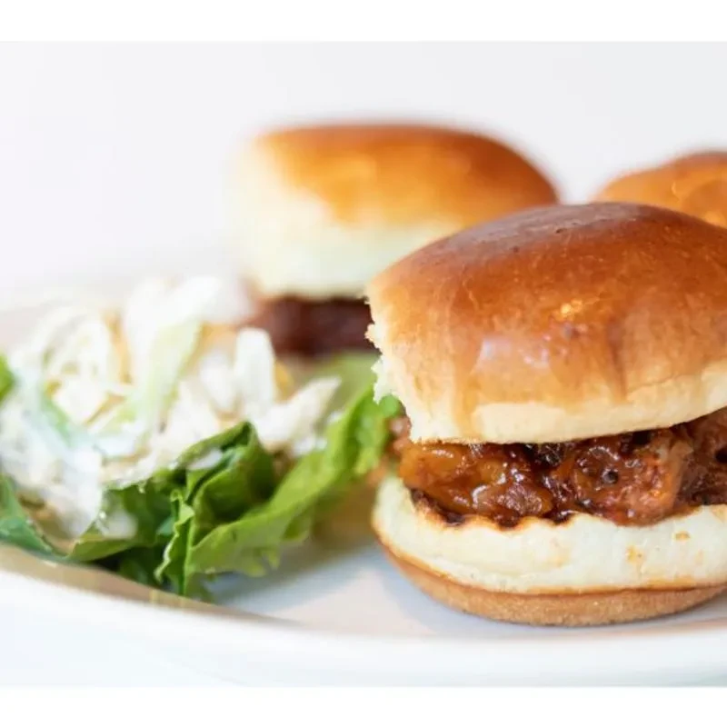 Three golden-brown sliders with dark filling, served with a side salad.