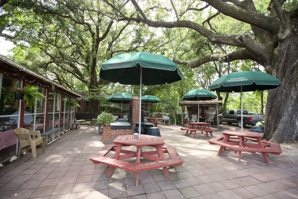 Shaded Seewee Restaurant patio with rustic wooden picnic tables.