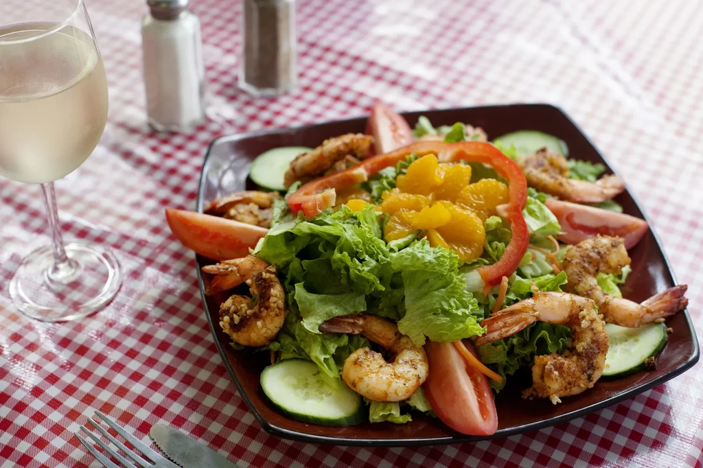 Seasoned shrimp salad, white wine, on a red and white checkered tablecloth.
