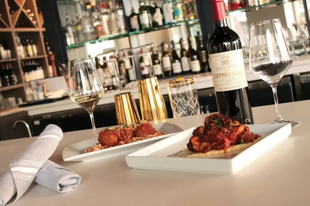 Appetizers, wine, and cocktail shakers on a bar counter.