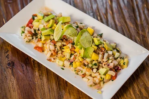 Finely diced seafood salad with mango, avocado, and lime on white plate.