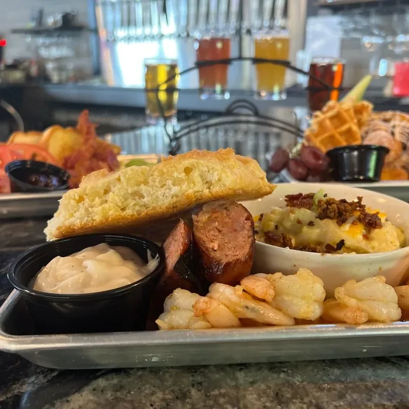 Metal tray with biscuit, sausage, shrimp, mashed potatoes, and gravy.