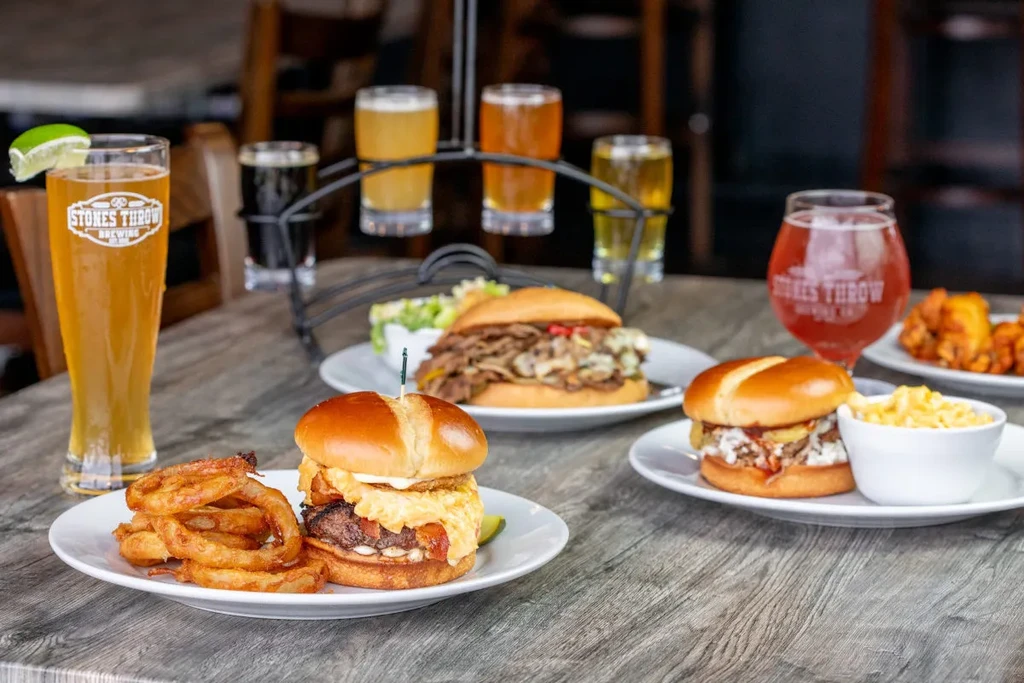 Burgers, sides, and a craft beer flight on a wooden table.