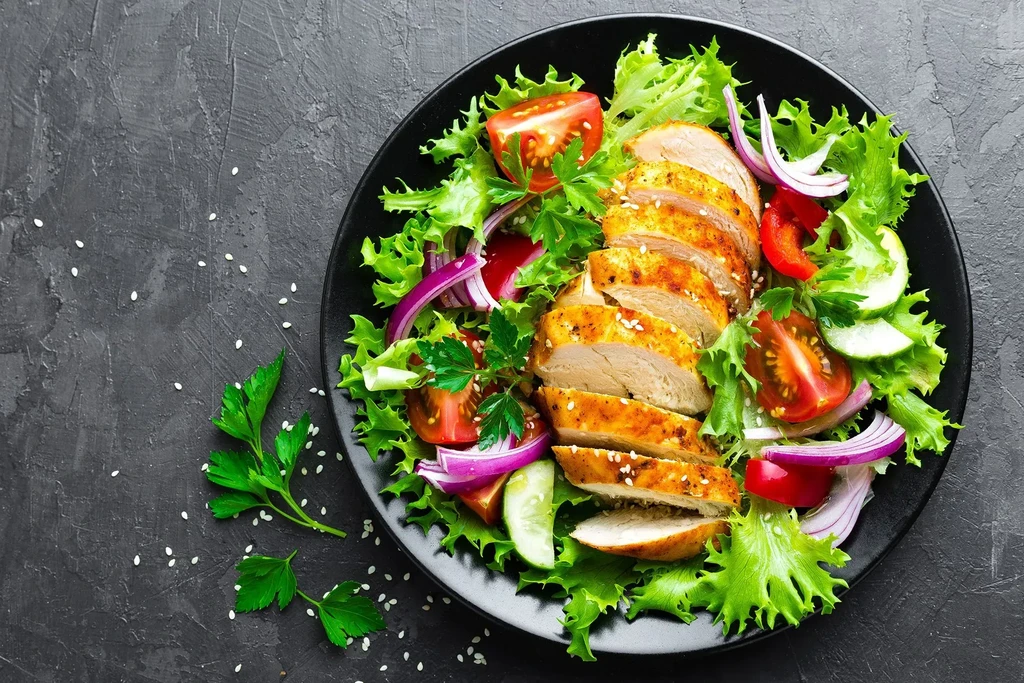 Grilled chicken breast salad with fresh vegetables and sesame seeds.