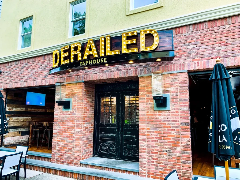 Derailed Tap House exterior with yellow and brick facade, ornate doors.