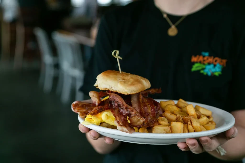 Close-up of a breakfast sandwich with eggs, bacon, and golden home fries.