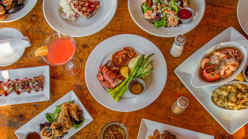 A rustic table overflowing with various seafood, meat, and drinks.